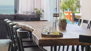 Een moderne eetruimte met een houten tafel en zwarte stoelen, een waterfles en een glazen waterkan op de tafel.