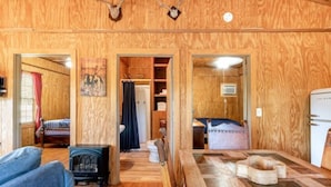 Interior de una cabaña de madera con una sala de estar acogedora, un baño a la vista y un comedor.