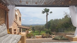 A bedroom with a view of a garden and palm tree, a wooden bed, and a small table. - Esturonet, Finca 5EstrellasHome Mallorca (Manacor)
