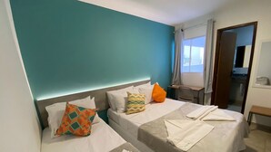 A hotel room with two beds, teal walls, and a small desk with a chair. - Pousada Mirante dos Corais (Ipojuca)
