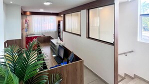 A reception area with a wooden desk, computer, and a plant. - Pousada Mirante dos Corais (Ipojuca)