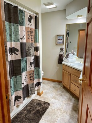 A bathroom with a shower curtain featuring animal prints, a sink, a mirror, and a rug. - 3 BR-Hot Tub-Easy Access-Close to Strip-Mtn Views (Sevierville)