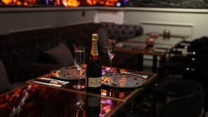 A dining table with a bottle of champagne, a glass, and a plate with food remnants. - Mas Suites Karaköy (Istanbul)