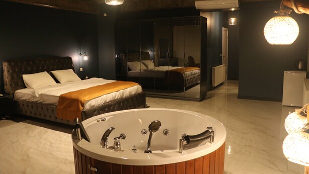 A modern bedroom with a large bed, a separate sitting area, a walk-in closet, and a freestanding bathtub. - Mas Suites Karaköy (Istanbul)