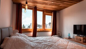 A bedroom with a large bed, a TV on a wooden stand, and a window with curtains. - Immodreams - Le Lodge - Avoriaz (Avoriaz)