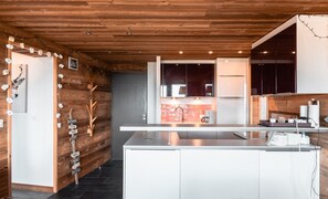 A modern kitchen with wooden walls, a central island, and a built-in oven.