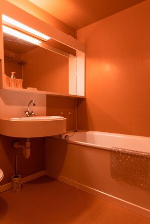 A bathroom with a sink, mirror, and bathtub.