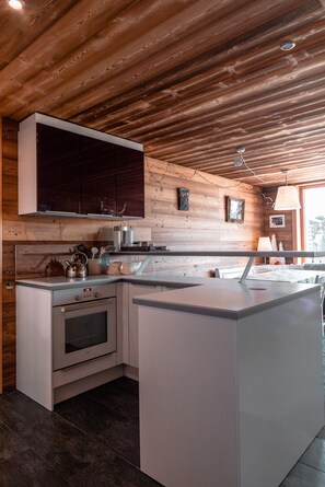 Une cuisine moderne avec un plafond en bois, des meubles de couleur sombre et un îlot central.