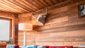 A cozy room with a wooden ceiling, a red sofa with colorful cushions, a lamp, and a deer head mounted on the wall. - Immodreams - Le Lodge - Avoriaz (Avoriaz)
