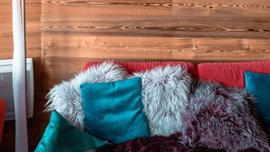 A wooden ceiling with a mounted animal skull, a red sofa with various pillows, and a white floor lamp. - Immodreams - Le Lodge - Avoriaz (Avoriaz)