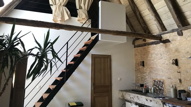 A rustic interior with a wooden staircase, a kitchen area with a stone wall, and a hanging basket. - 3 Bedroom Private vacation home in Saint-Cyprien (Saint-Cyprien)
