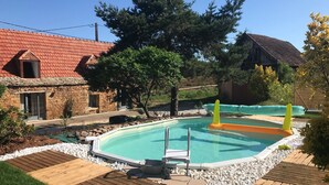 A swimming pool with a wooden deck, surrounded by white pebbles and greenery. - 3 Bedroom Private vacation home in Saint-Cyprien (Saint-Cyprien)