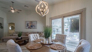 A modern living room with a round wooden table, beige sofas, and a ceiling fan. - Backyard Paradise in the Valley! Pool/Jacuzzi! (San Tan Valley)