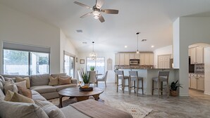 A spacious living room with a large sofa, a coffee table, and a dining area with chairs. - Backyard Paradise in the Valley! Pool/Jacuzzi! (San Tan Valley)