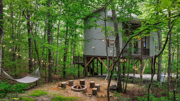 A treehouse with a deck and a fire pit surrounded by trees. - Serenity Escape Treehouse on 14 Acres with easy trails, fire pit and hammock. (Fort Payne)