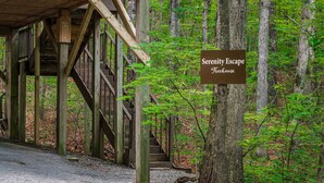 A wooden staircase leading to a covered area labeled 'Serenity Escape Treehouse'. - Serenity Escape Treehouse on 14 Acres with easy trails, fire pit and hammock. (Fort Payne)