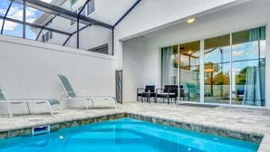 A swimming pool with lounge chairs and a glass door leading to an outdoor area.