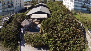 Un resort con un pabellón de techo de paja, asientos al aire libre y vista al mar.