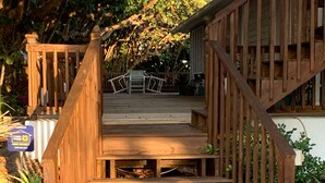 Una escalera de madera que lleva a una terraza con mobiliario exterior.