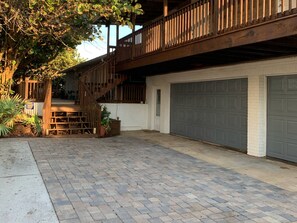 A two-story house with a wooden staircase, a garage, and a paved driveway.