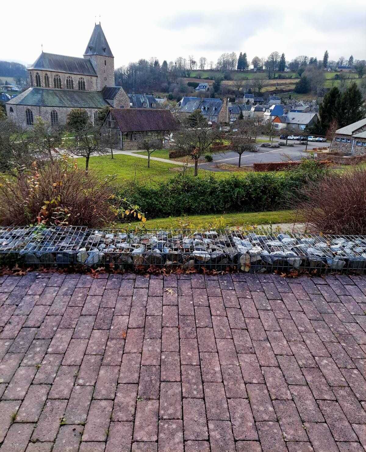 A paved area with a stone wall and a metal fence, likely a parking area.