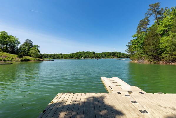 A wooden dock extending into a calm lake surrounded by lush greenery.