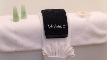 A neatly folded white towel with a black towel labeled "Makeup" and two green bottles of shampoo and conditioner.