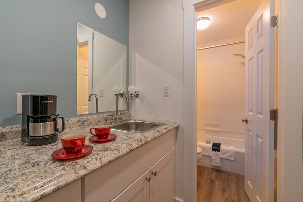 A bathroom with a sink, mirror, and shower.