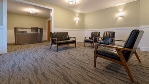 A carpeted room with four leather chairs, a wooden table, and two wall-mounted light fixtures. - Moultonborough Inn (Moultonborough)