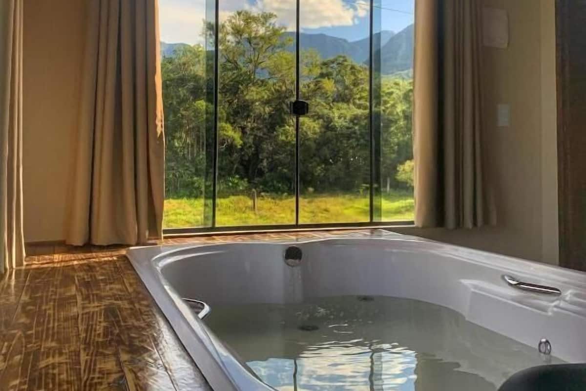 Habitación con un amplio ventanal que ofrece vistas a la vegetación y montañas.
