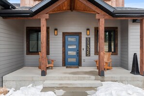 A house with a blue door, two wooden chairs on the porch, and a number sign above the door. - Copper Skies Lodge In Powder House Pass (South Lawrence)