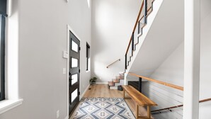 A narrow hallway with a patterned rug, a wooden bench, and a staircase with a wooden handrail. - Copper Skies Lodge In Powder House Pass (South Lawrence)