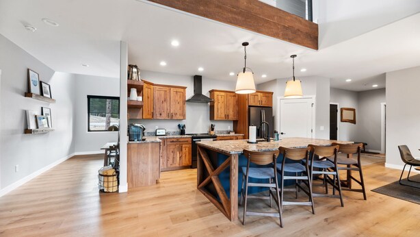 A modern kitchen with wooden cabinets, a large island, and pendant lighting. - Copper Skies Lodge In Powder House Pass (South Lawrence)