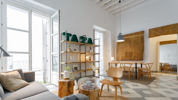 Una sala de estar moderna con sofá, mesa de centro y un comedor con sillas y una mesa.