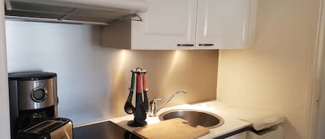 A compact kitchenette with a toaster, coffee maker, and a sink.