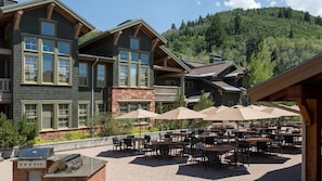 Enjoy al fresco dining and cooking on the outdoor patio, featuring tables, chairs, and a barbecue grill.