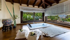 Quarto com uma janela grande, banheira, toalhas e uma tigela decorativa.