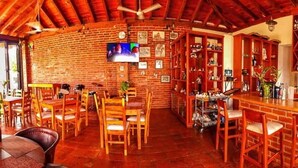 A cozy bar area with wooden furniture, brick walls, and a television mounted on the wall. - Hotel Milin (Villa Comaltitlán)