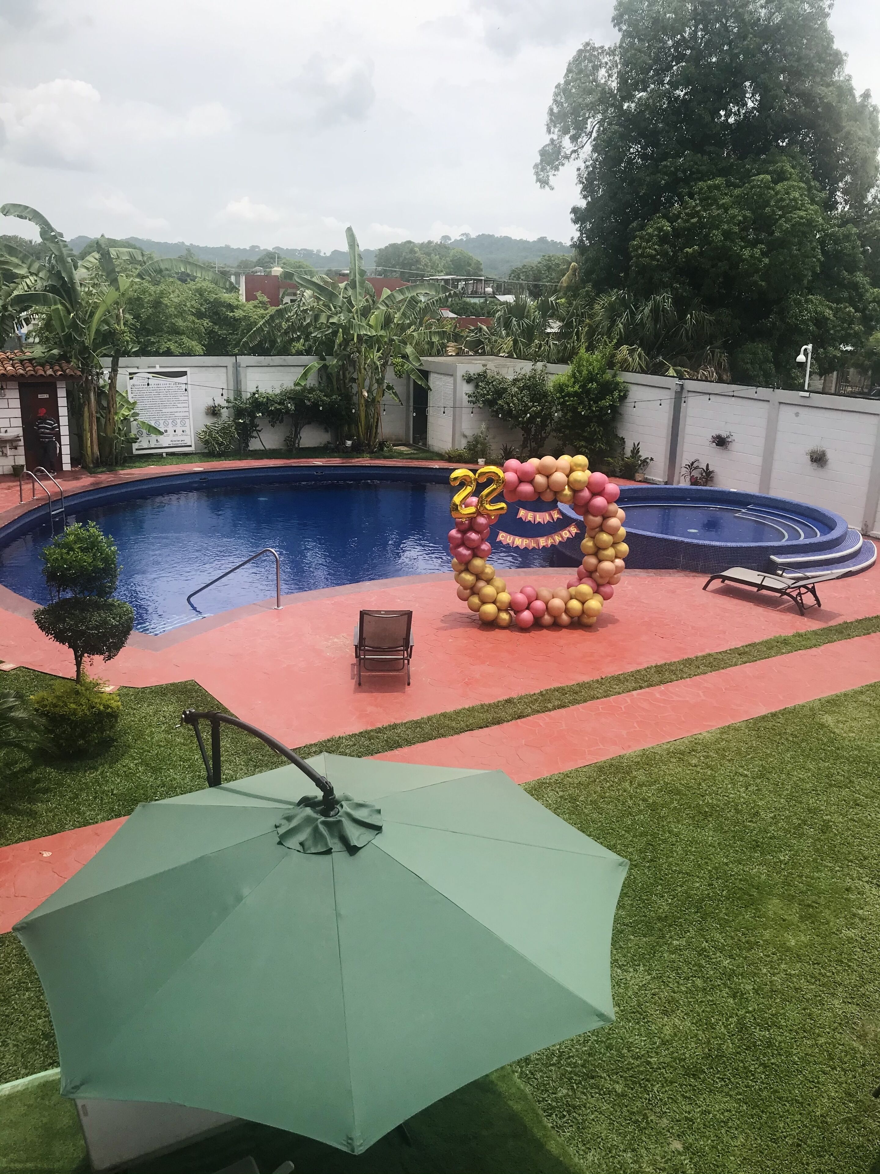 A swimming pool with a decorative balloon arch and a chair.