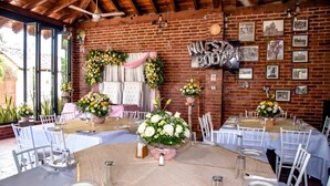 A restaurant with brick walls, white tables, and floral centerpieces. - Hotel Milin (Villa Comaltitlán)