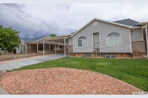 Situated in a suburban setting, this single-story house features a covered front porch and a landscaped yard with a mix of grass and gravel.