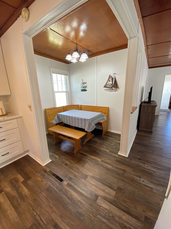 A bedroom with a wooden bed, a bench, a small table, and a ceiling light fixture. - Cottage by the Beach (Shawano)