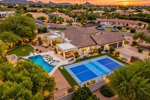 A residential property with a swimming pool, tennis court, and landscaped garden.