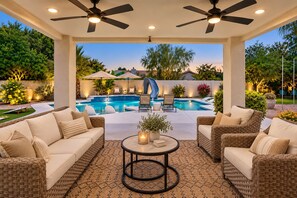 A covered outdoor seating area with wicker furniture, a pool, and a slide.