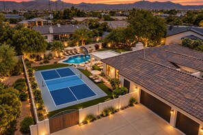 A residential property with a tennis court, swimming pool, and a landscaped backyard.