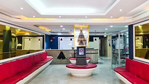 A hotel lobby with a reception desk, red seating, and a decorative fountain. - Hotel Sao Luiz (Aparecida)