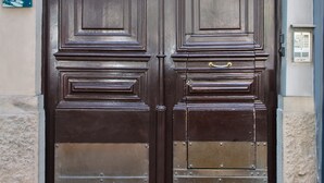 A double wooden door with a decorative metal grille and a circular medallion in the center. - Enjoy Art (Naples)