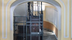 A grand staircase with a metal railing, leading to an upper floor. - Enjoy Art (Naples)