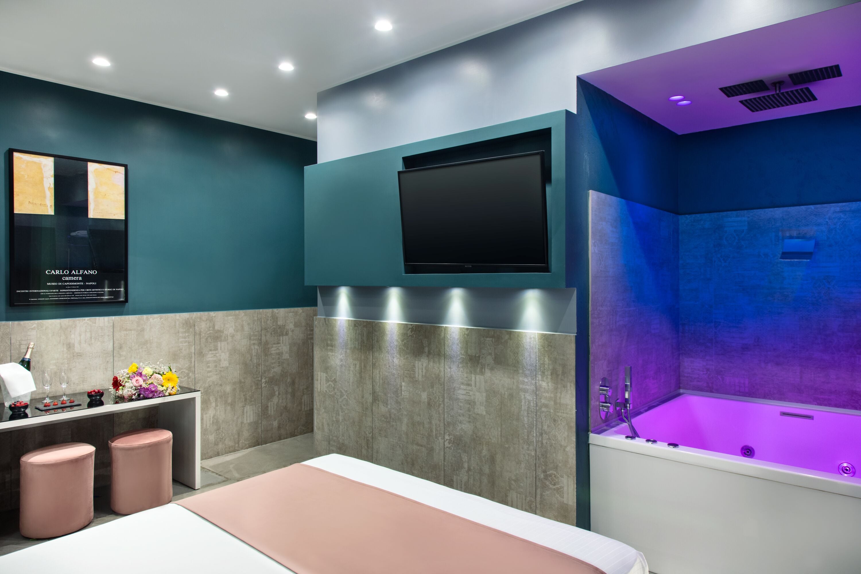 A modern bathroom with a large bathtub, a flat-screen TV mounted on the wall, and a vanity with a mirror and countertop.