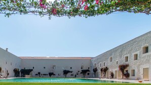 A courtyard with a swimming pool, lounge chairs, and a white building with arched windows. - Convento das Bernardas Lux T2 Triplex (Tavira)
